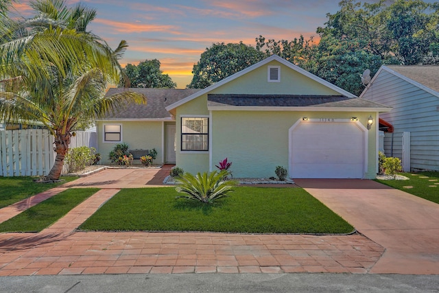 view of front of house featuring a front lawn, fence, concrete driveway, stucco siding, and a garage