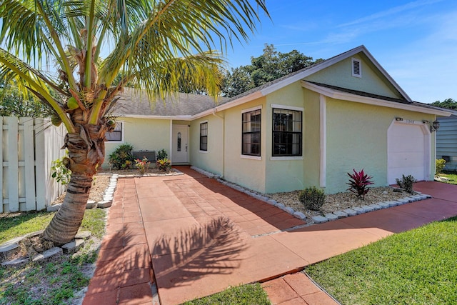 view of front of house with an attached garage, fence, and stucco siding