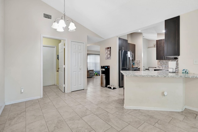 kitchen featuring visible vents, backsplash, a peninsula, freestanding refrigerator, and arched walkways