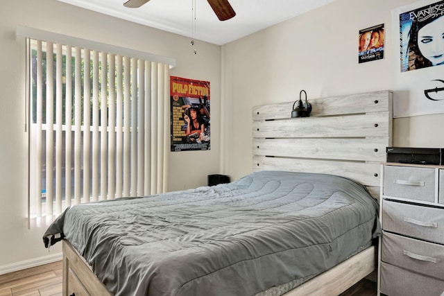 bedroom with multiple windows, wood finished floors, baseboards, and ceiling fan