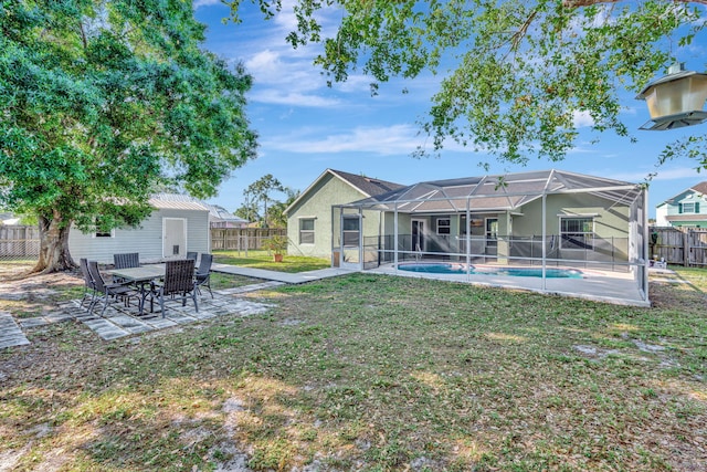 rear view of property featuring a fenced backyard, glass enclosure, an outdoor structure, a fenced in pool, and a patio area