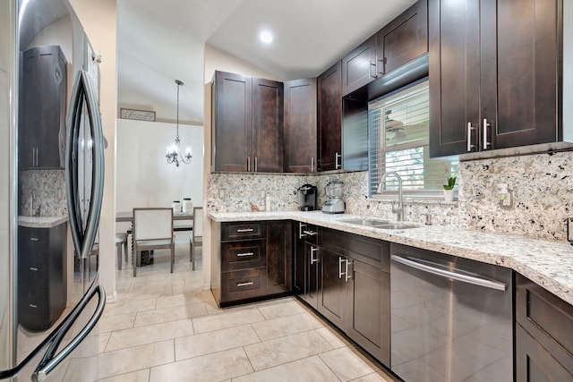 kitchen with light stone countertops, a sink, vaulted ceiling, dark brown cabinets, and appliances with stainless steel finishes