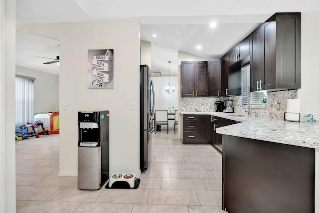 kitchen with tasteful backsplash, dark brown cabinetry, freestanding refrigerator, a ceiling fan, and a sink