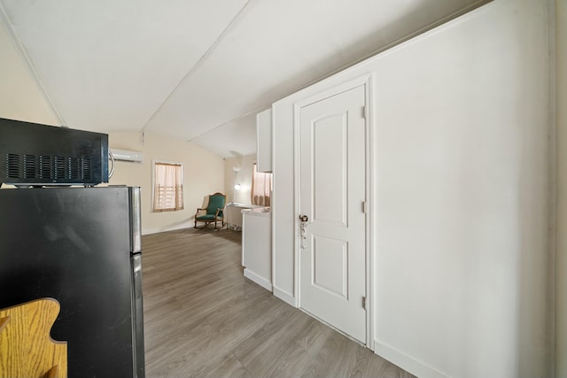 kitchen featuring vaulted ceiling, light wood-style flooring, baseboards, and freestanding refrigerator