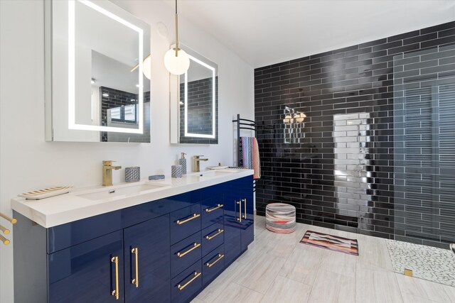 bathroom featuring double vanity, tile walls, a tile shower, and a sink