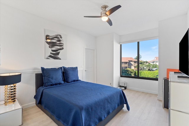 bedroom with a ceiling fan, baseboards, and light wood-type flooring