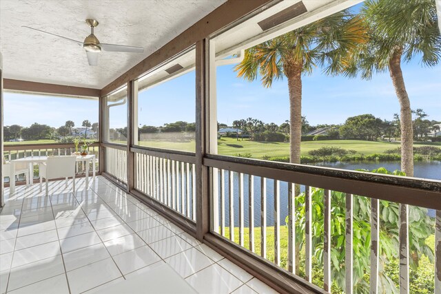 sunroom / solarium featuring a water view and ceiling fan