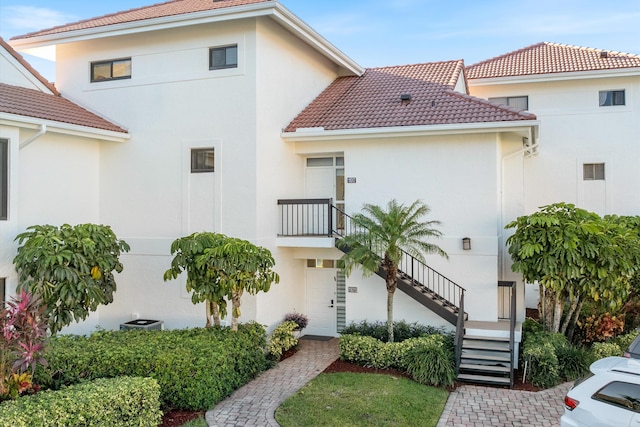 mediterranean / spanish home with stucco siding, stairway, and a tile roof