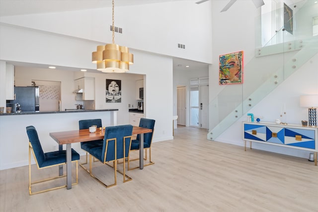 dining space with visible vents, light wood-style flooring, and stairs