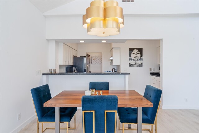 dining area with visible vents, light wood-type flooring, baseboards, and vaulted ceiling