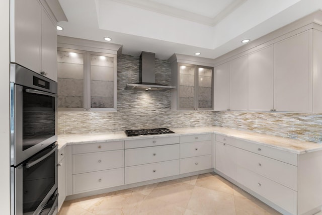 kitchen with tasteful backsplash, glass insert cabinets, stainless steel appliances, and wall chimney exhaust hood