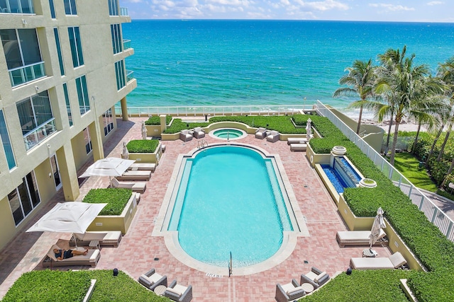 pool featuring a patio area, a community hot tub, and a water view