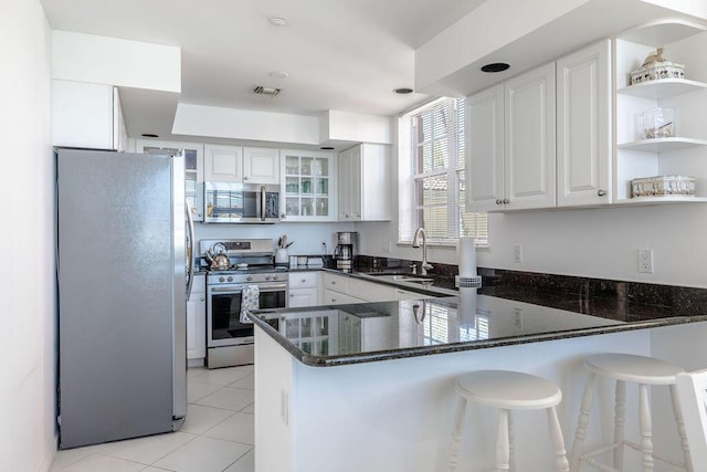 kitchen featuring visible vents, a sink, a peninsula, stainless steel appliances, and open shelves