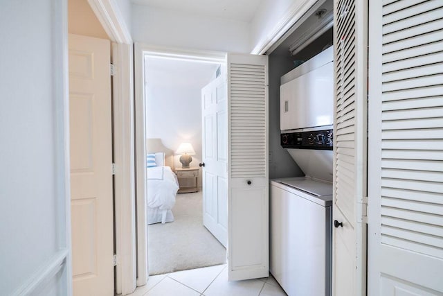 laundry area featuring light tile patterned floors, light carpet, stacked washer and dryer, and laundry area