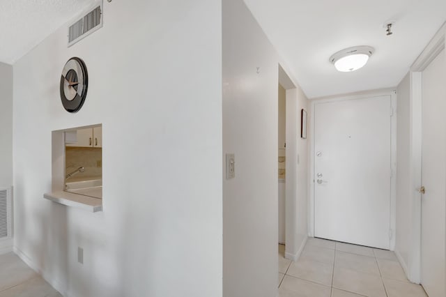 corridor with light tile patterned floors, visible vents, and baseboards