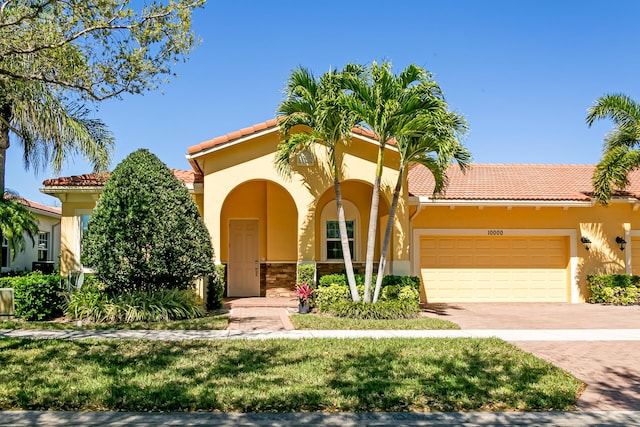 mediterranean / spanish house with stucco siding, decorative driveway, and a garage