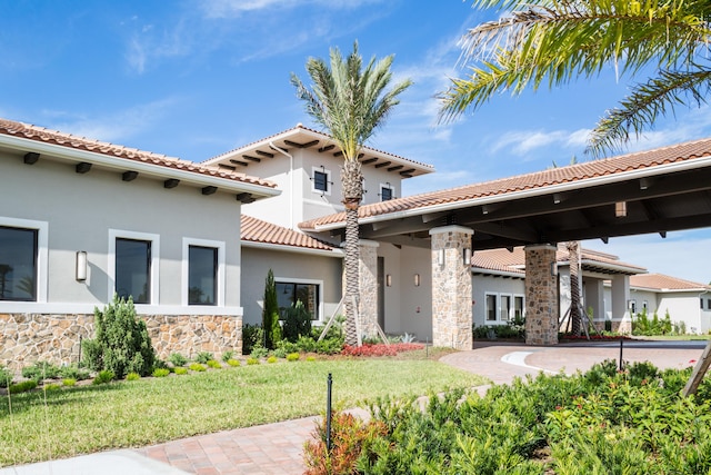 exterior space with a tiled roof, a yard, stone siding, and stucco siding