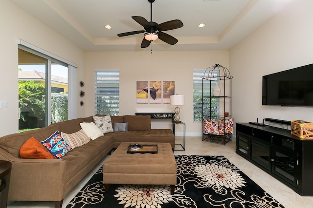 living room with a wealth of natural light, a raised ceiling, and light tile patterned flooring