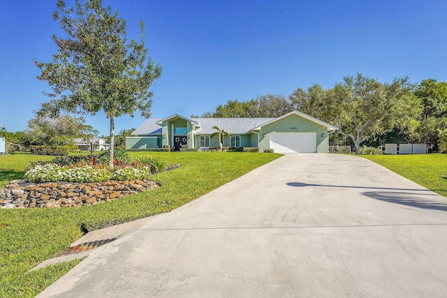 ranch-style home with an attached garage, concrete driveway, a front yard, and metal roof