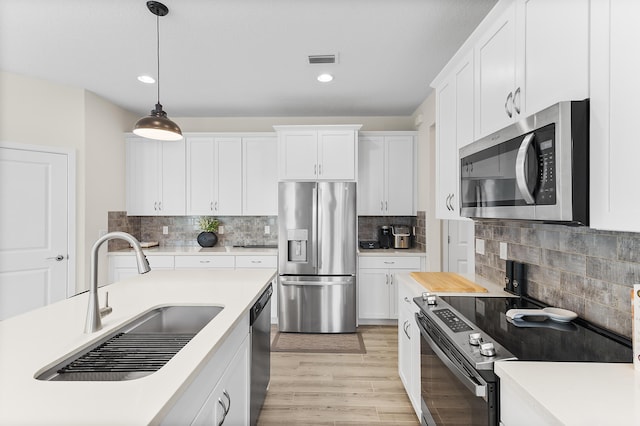 kitchen with visible vents, a sink, appliances with stainless steel finishes, white cabinets, and light countertops