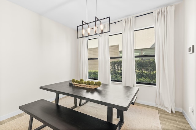 dining area with baseboards, an inviting chandelier, and light wood-style flooring