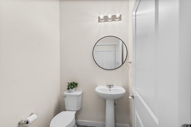 half bathroom featuring baseboards and toilet