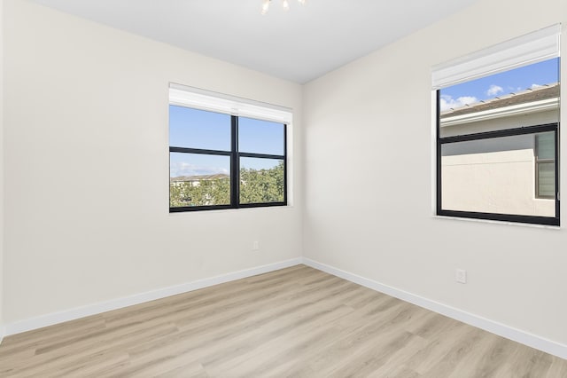 unfurnished room with light wood-style flooring and baseboards