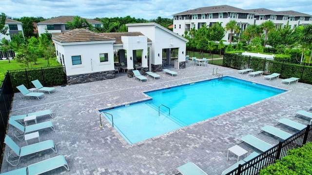 community pool featuring a patio, an outdoor structure, and fence