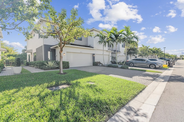 view of front of house featuring a front lawn, decorative driveway, an attached garage, and stucco siding