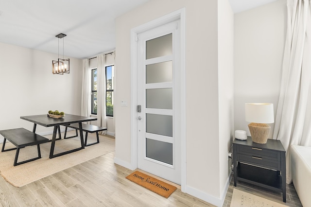 dining space featuring light wood finished floors, a notable chandelier, and baseboards