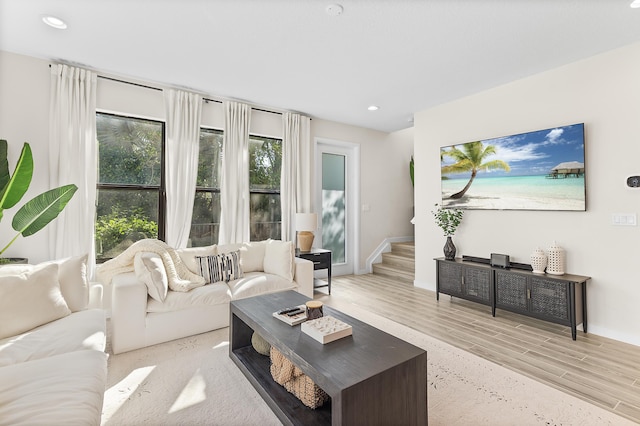 living room featuring stairs, light wood-style flooring, recessed lighting, and baseboards