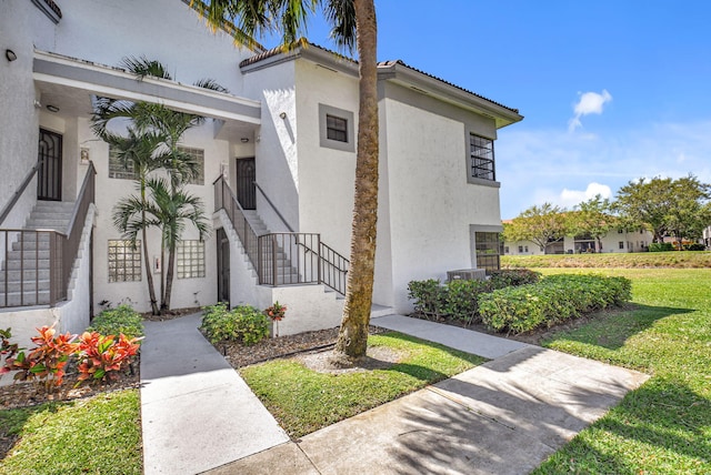 property entrance featuring a yard and stucco siding