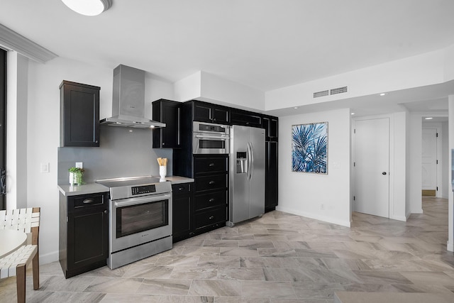 kitchen featuring visible vents, light countertops, appliances with stainless steel finishes, dark cabinetry, and wall chimney exhaust hood