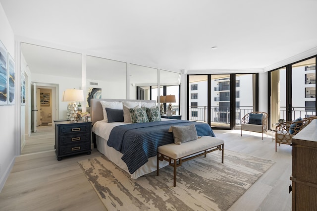 bedroom with expansive windows, baseboards, light wood-style flooring, and access to exterior