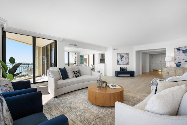 living area featuring light wood-type flooring, visible vents, and floor to ceiling windows