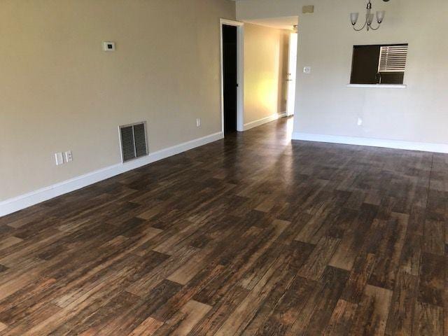 spare room with visible vents, dark wood-type flooring, and baseboards