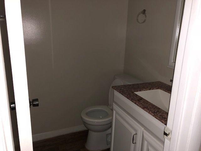 half bathroom featuring baseboards, toilet, and vanity