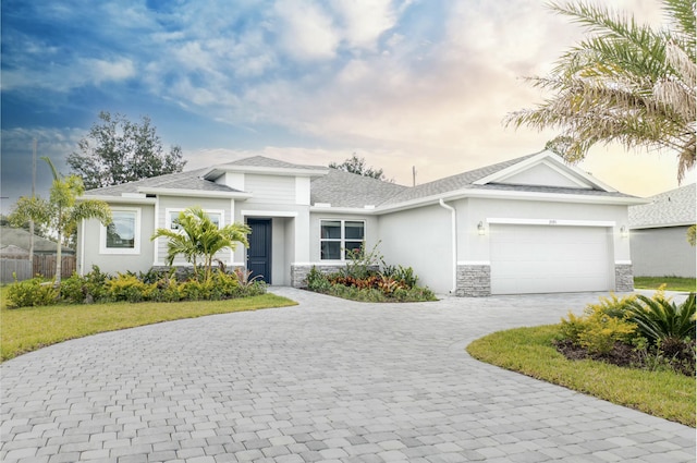 view of front facade with decorative driveway, a garage, stone siding, and stucco siding