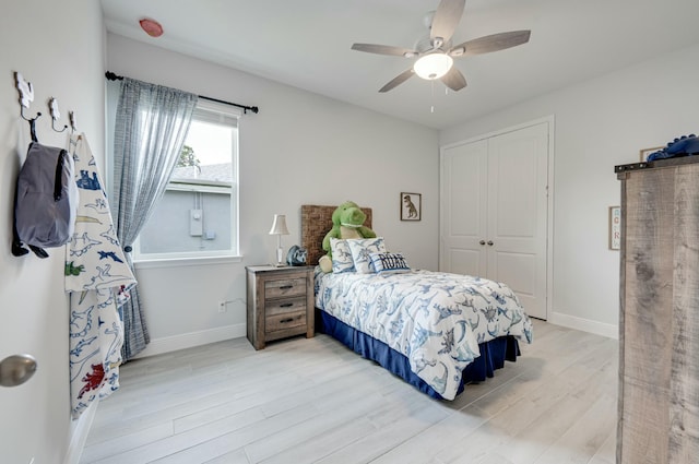 bedroom with baseboards, a closet, light wood finished floors, and ceiling fan