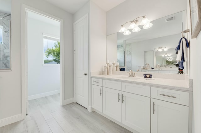 bathroom featuring vanity, wood finished floors, baseboards, visible vents, and a marble finish shower