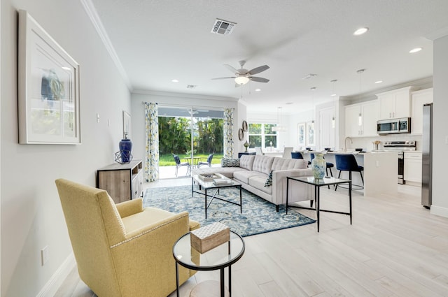 living room with visible vents, recessed lighting, ceiling fan, ornamental molding, and light wood-type flooring