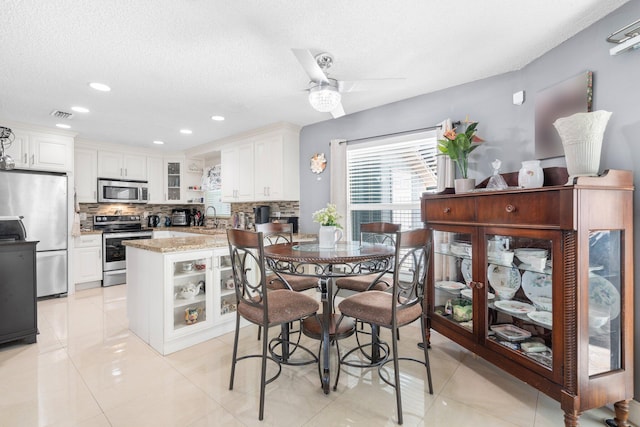 dining space with light tile patterned floors, visible vents, a textured ceiling, and ceiling fan