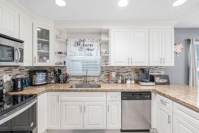 kitchen with white cabinetry, open shelves, appliances with stainless steel finishes, and a sink