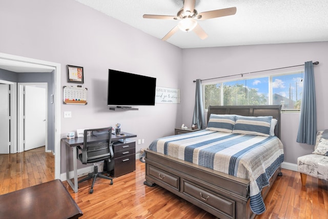 bedroom with a ceiling fan, baseboards, lofted ceiling, light wood-style floors, and a textured ceiling