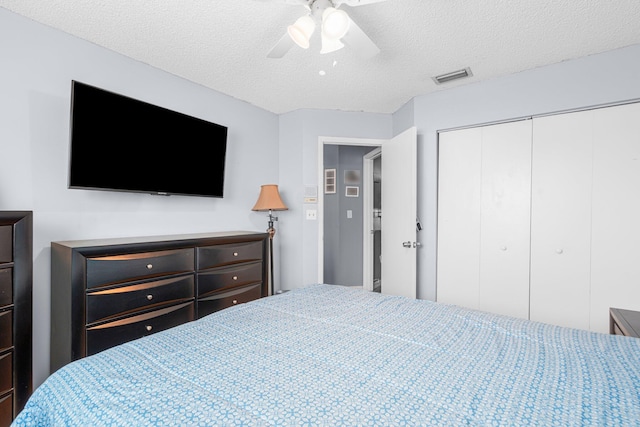 bedroom featuring a closet, visible vents, a textured ceiling, and ceiling fan