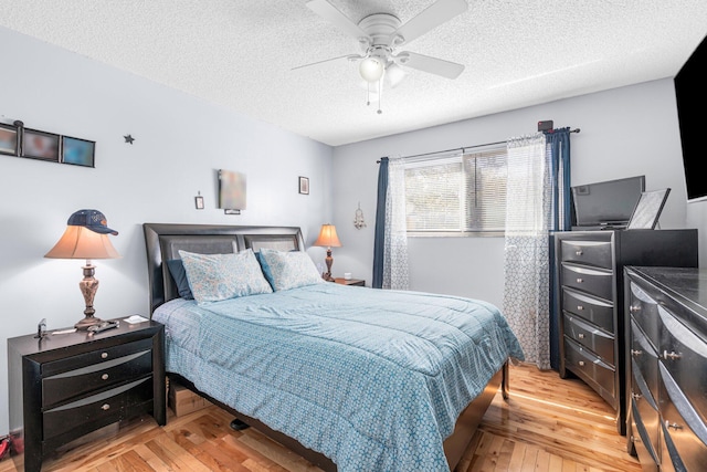 bedroom featuring light wood finished floors, a textured ceiling, and ceiling fan