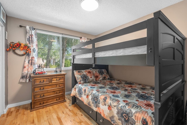 bedroom with baseboards, wood-type flooring, and a textured ceiling