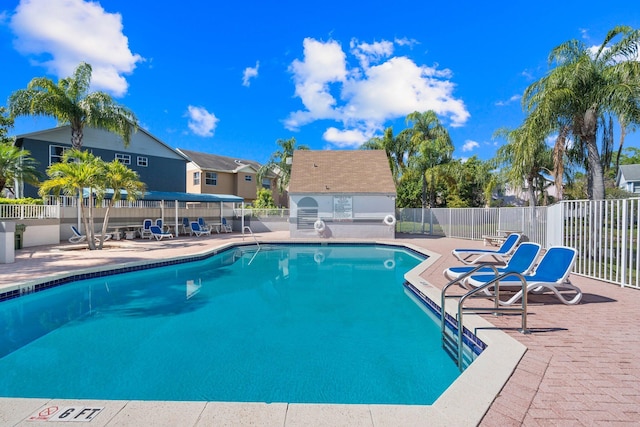 pool with a patio area, a residential view, and fence