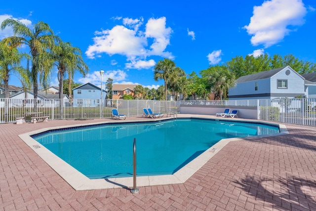 community pool with a patio, fence, and a residential view