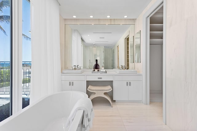 full bath with double vanity, recessed lighting, a freestanding tub, and a sink